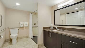 Ein Badezimmer mit Toilette, Waschbecken, Spiegel und Duschbereich.
