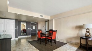 A hotel room with a dining area featuring a table and chairs, a kitchen area, and a bathroom visible through an open door. - The Carriage House (Las Vegas)