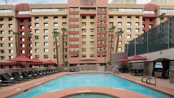 A hotel with a pool area, including lounge chairs and umbrellas.