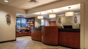 A hotel reception area with a counter, a computer, and a wall decorated with holiday wreaths. - The Carriage House (Las Vegas)