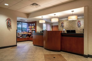 A hotel reception area with a counter, a computer, and a wall decorated with holiday wreaths. - The Carriage House (Las Vegas)