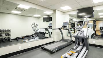 A gym with exercise equipment, a treadmill, and a mirrored wall.