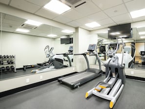 A gym with exercise equipment, a treadmill, and a mirrored wall.