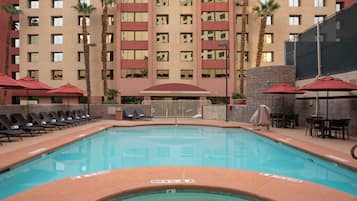 Un espace piscine d’hôtel avec une piscine à eau claire, des chaises longues et des palmiers.