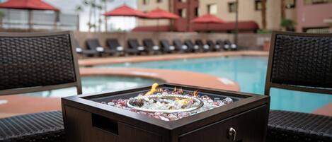 A poolside area with lounge chairs and a fire feature.