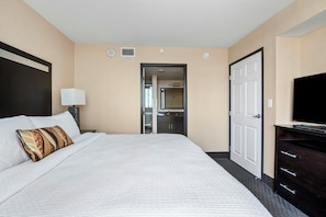 A hotel room with a large bed, a television, a desk, and a bathroom visible through an open door. - The Carriage House (Las Vegas)