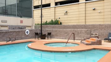 A swimming pool with a hot tub, a lifeguard chair, and a sign indicating a 5 ft depth.