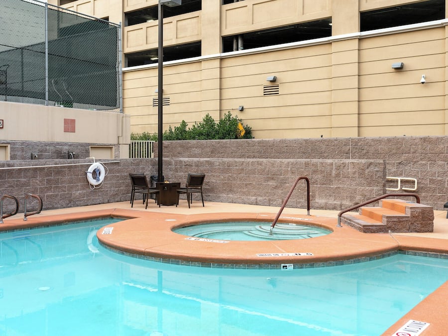 A swimming pool with a hot tub, a lifeguard chair, and a sign indicating a 5 ft depth.