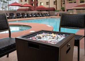 A poolside area with lounge chairs and a fire feature. - The Carriage House (Las Vegas)