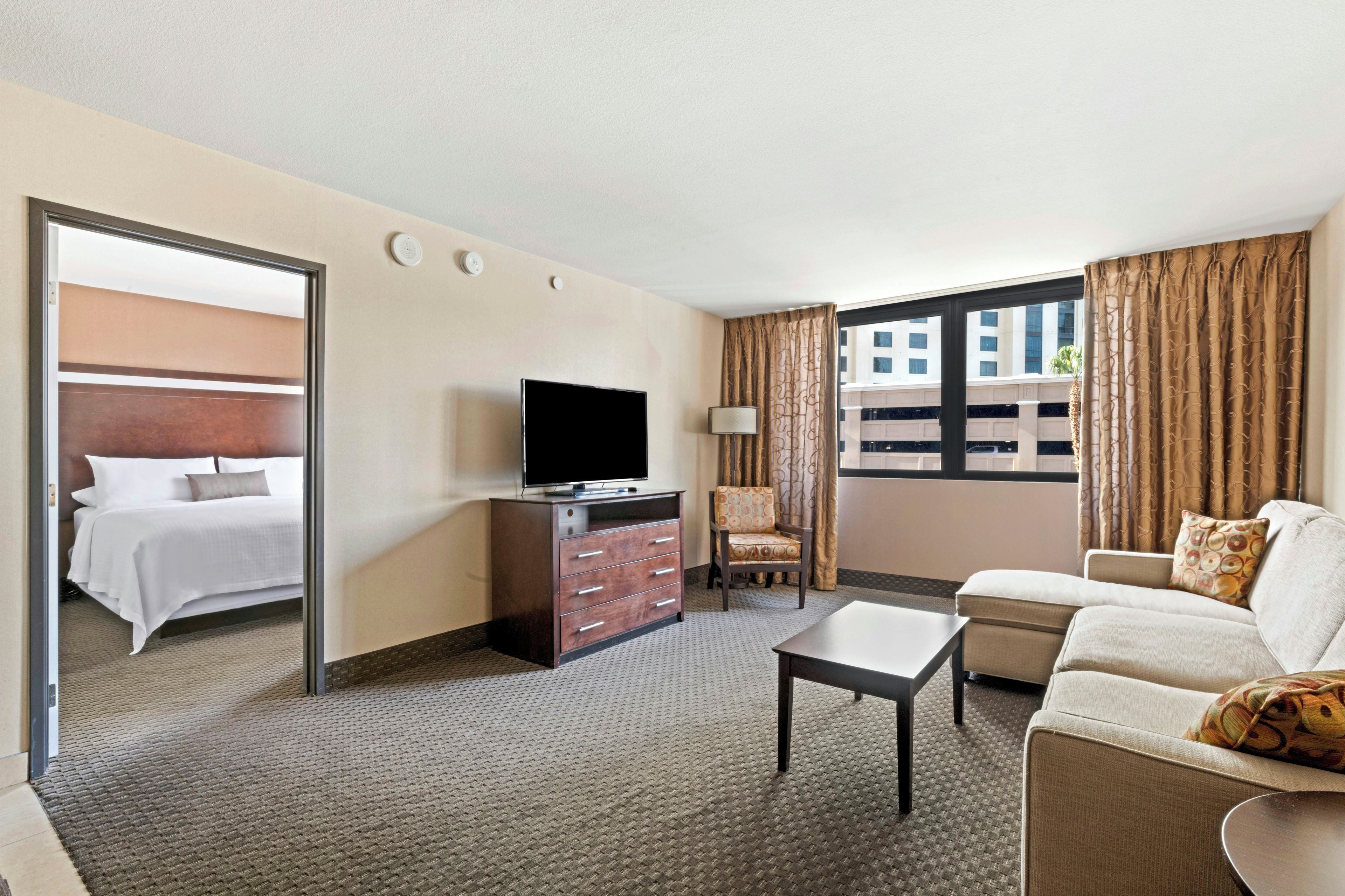 Una habitación de hotel con cama, televisor, sofá, sillón y escritorio.
