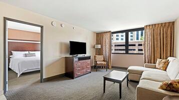 Una habitación de hotel con cama, televisor, sofá, sillón y escritorio.