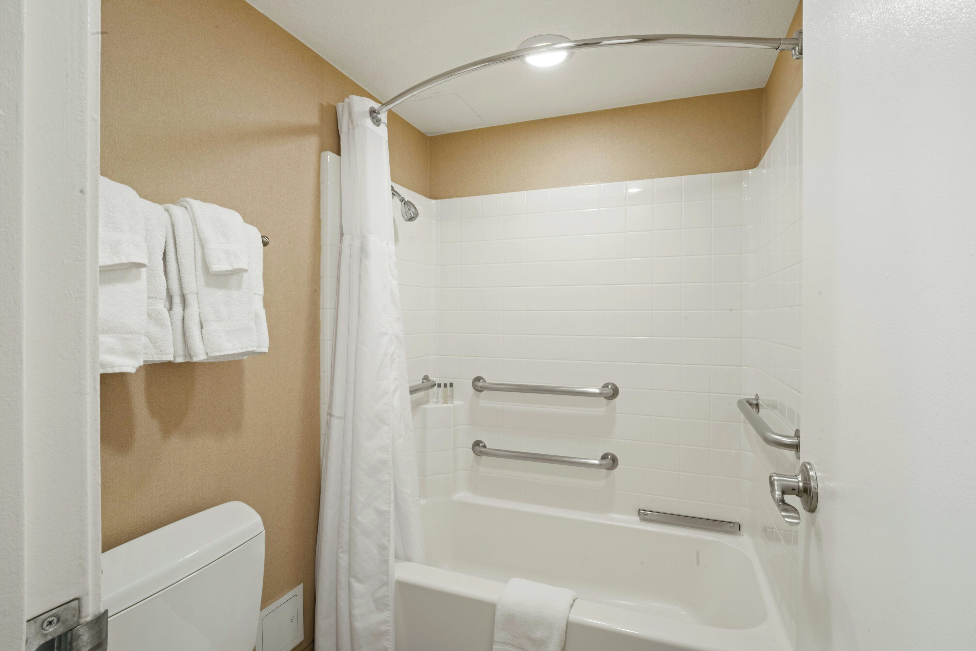 A bathroom with a bathtub, a shower curtain, and a toilet.