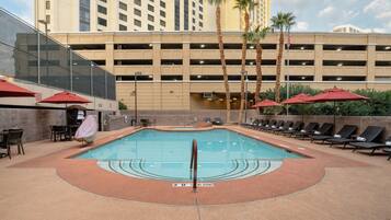 A hotel pool area with a clear water surface, sun loungers, and a no diving sign.