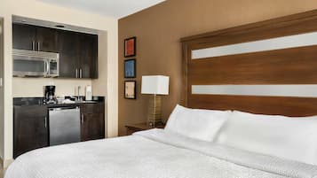 A hotel room with a bed, a desk with a lamp, a microwave, and a coffee maker.