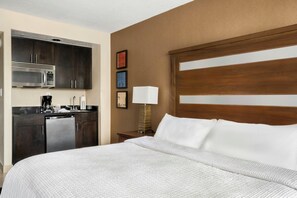 A hotel room with a bed, a desk with a lamp, a microwave, and a coffee maker.