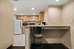 A compact kitchen with a refrigerator, microwave, stove, and a coffee maker.