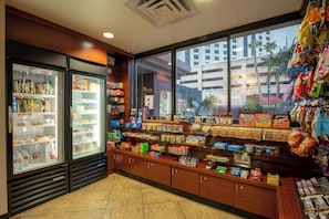 A convenience store with refrigerated sections, shelves stocked with snacks, and a view of a building outside. - The Carriage House (Las Vegas)