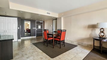 A hotel room with a dining area featuring a table and chairs, a kitchen area, and a bathroom visible through an open door.