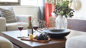 Une table en bois avec une bouteille de vin, des verres, du fromage, des raisins et un bol.