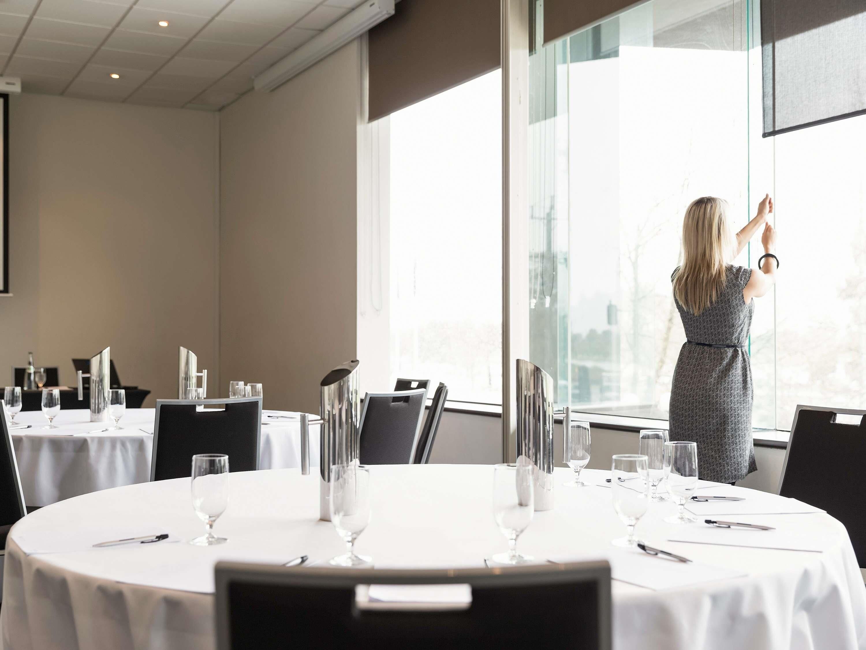 A conference room with round tables, chairs, and a large window.