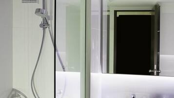 A modern bathroom with a glass-enclosed shower, a sink, and toiletries.