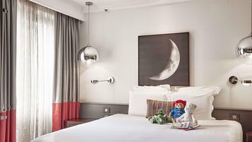 Una habitación de hotel con una cama grande, un cuadro de luna creciente colgado en la pared y dos lámparas de pared.