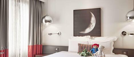 Ett hotellrum med en stor säng, en halvmånebild som hänger på väggen och två vägglampor.