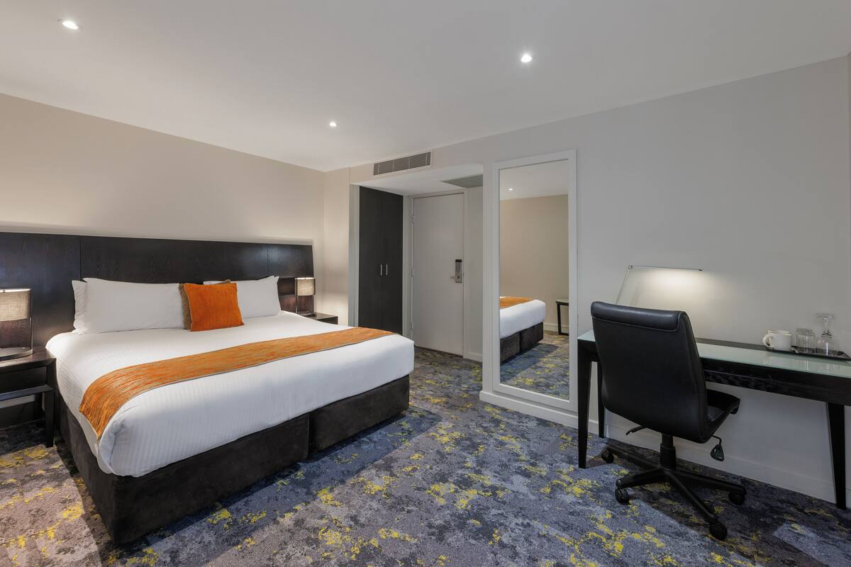 Hotellihuone, jossa on suuri sänky, työpöytä ja tuoli.
