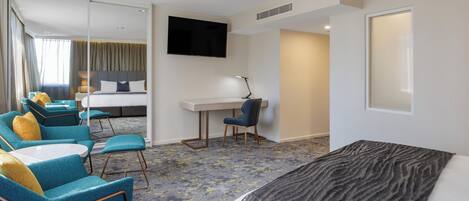A hotel room with a bed, a desk, a chair, and a TV.