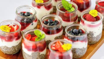 A tray of layered dessert cups with various fruits and a flower garnish.