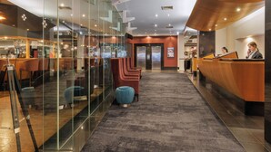Un moderno vestíbulo de hotel con mostrador de recepción, zona de estar y paredes de vidrio.