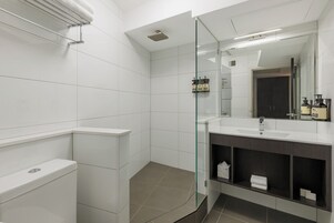 A modern bathroom with a glass shower enclosure, a white sink, and a dark vanity.