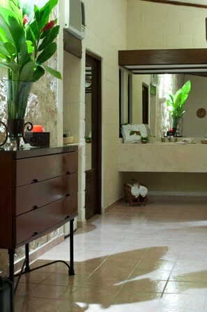 A bathroom with a wooden vanity, a mirror, and a potted plant.