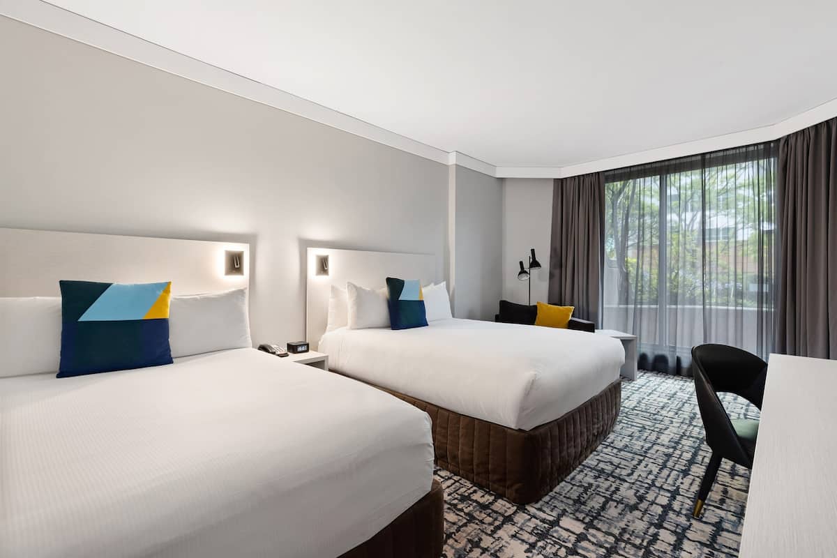 Een hotelkamer met twee bedden, een bureau en een stoel.