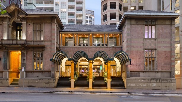 Un edificio histórico con una entrada imponente, varios pisos y una torre angular destacada.