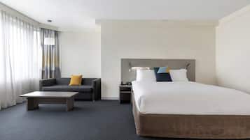 Una habitación de hotel con una cama grande, un sofá, una mesa de centro y una mesita de noche.