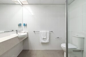 Une salle de bain moderne équipée d’un lavabo, d’un miroir, d’un porte-serviettes et de toilettes.