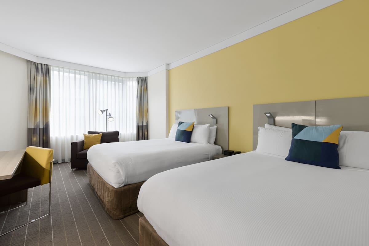 Een hotelkamer met twee bedden, een bureau en een stoel.