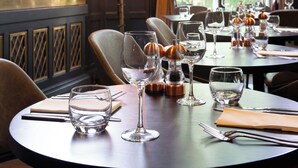 A dining area with tables set for a meal, a bar area with bottles, and a large window with curtains. - Elmbank York, Tapestry Collection by Hilton (York)
