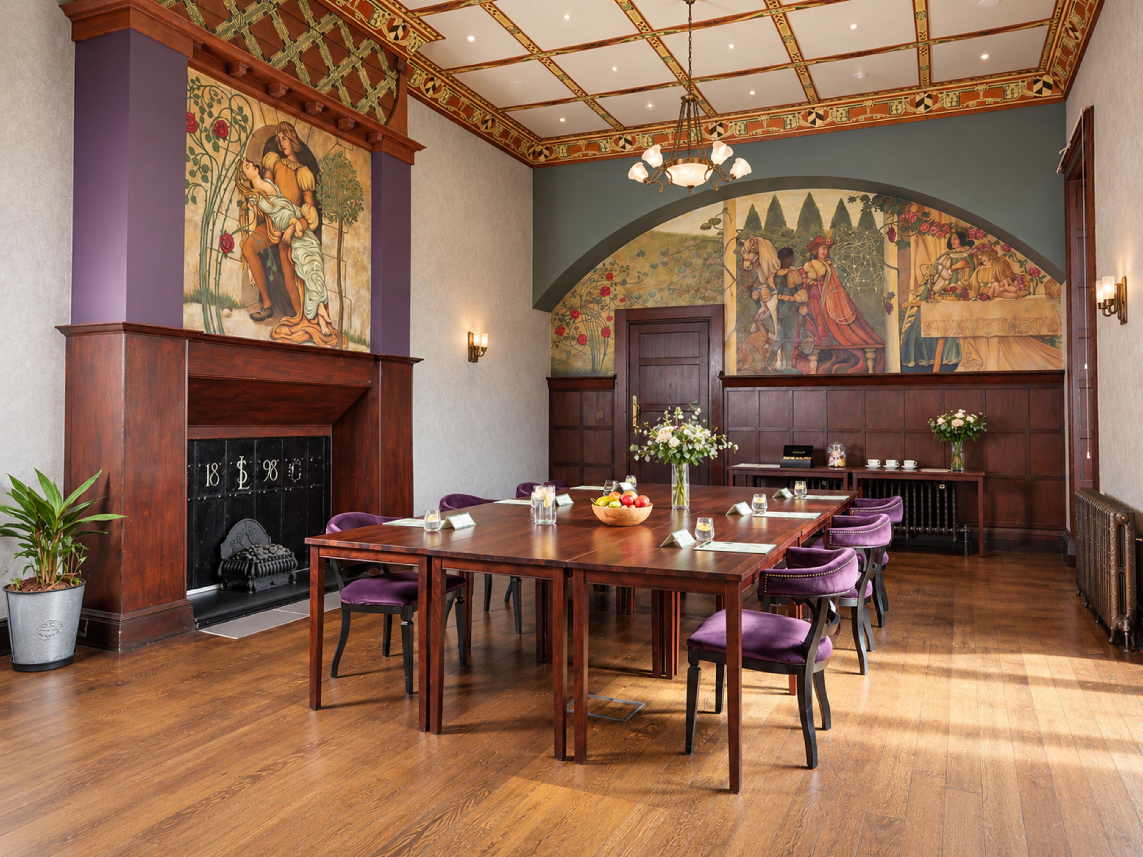 A formal dining room with a long table, chairs, and a fireplace.