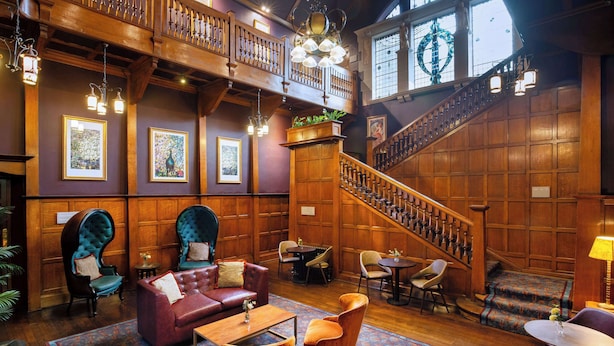 A spacious lobby with a grand staircase, wooden paneling, and comfortable seating areas. - Elmbank York, Tapestry Collection by Hilton (York)