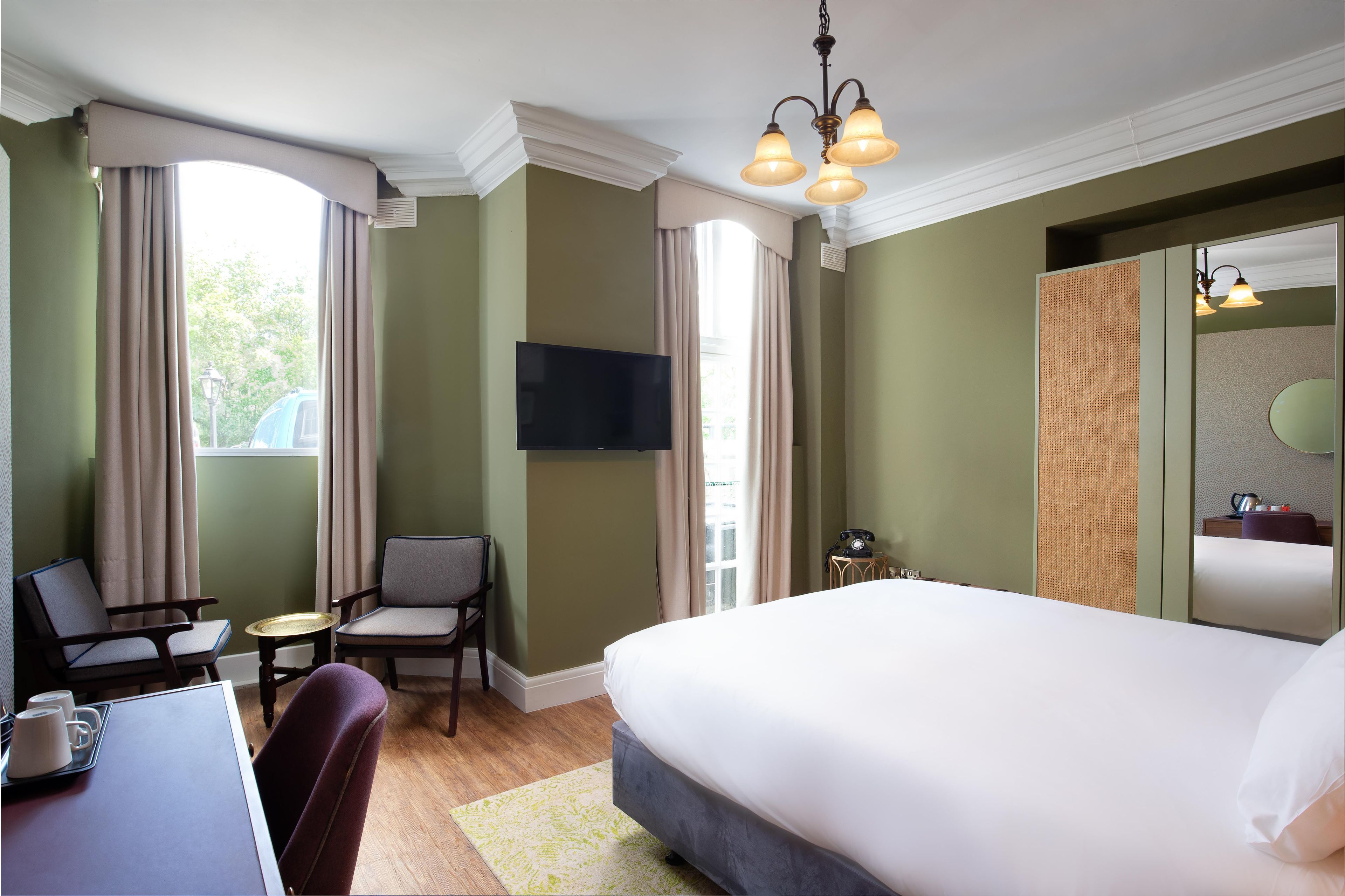 A hotel room with a bed, a desk with a chair, a television, and a telephone.