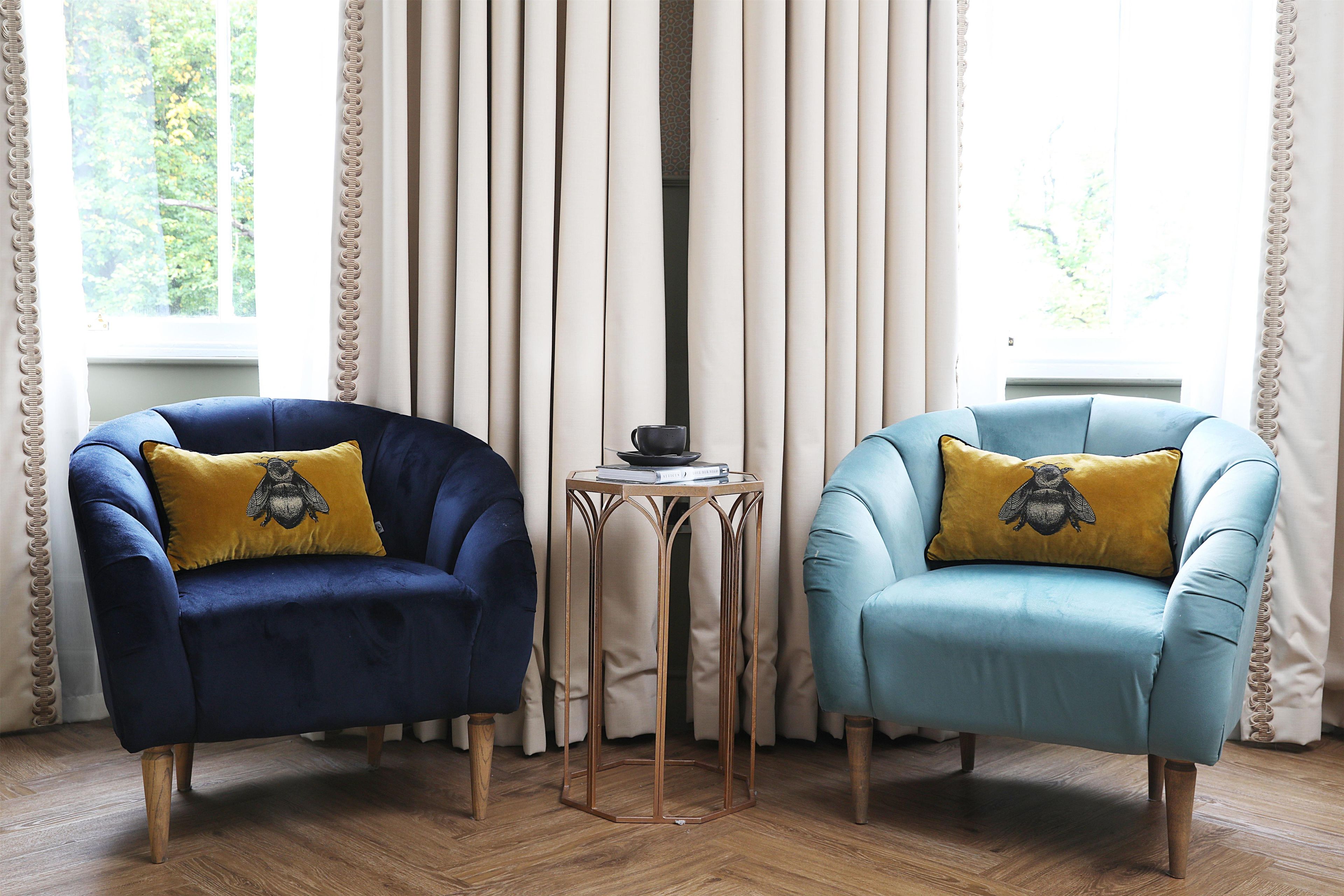 Two armchairs with yellow pillows, a small table, and a window with curtains.