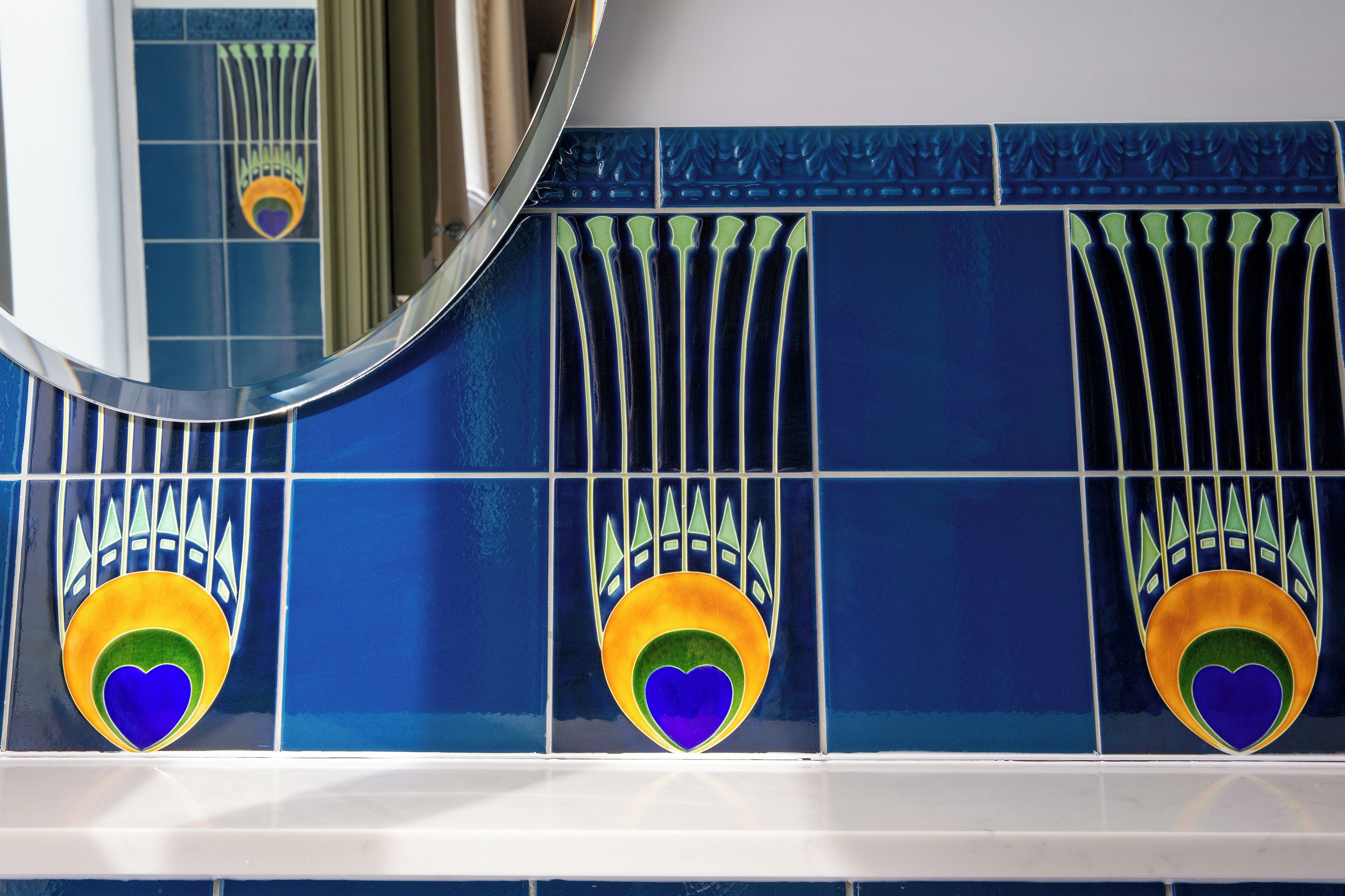 A bathroom with blue tiles and a mirror.