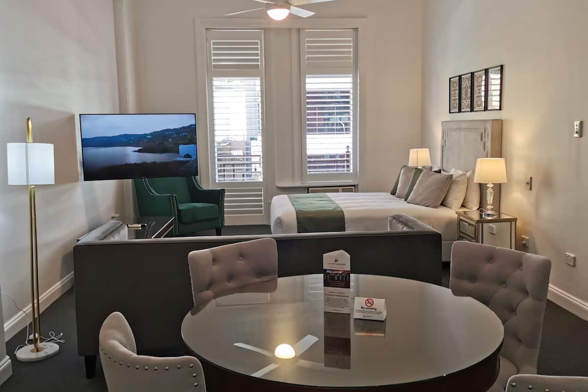 A hotel room with a bed, a TV, a dining table, and a seating area.