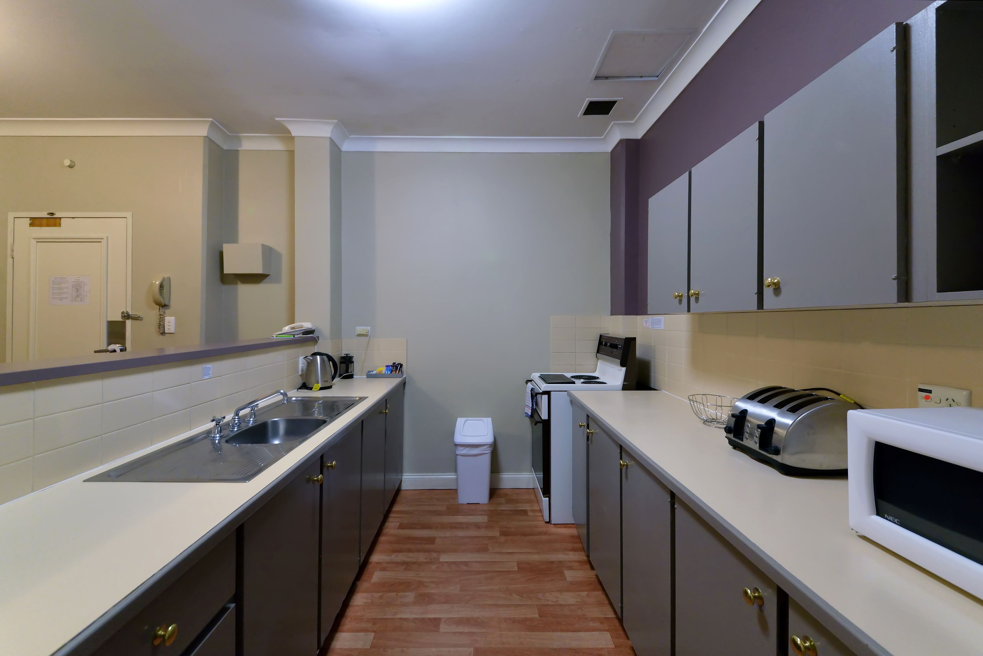 A kitchen with a sink, stove, microwave, toaster, and cabinets.