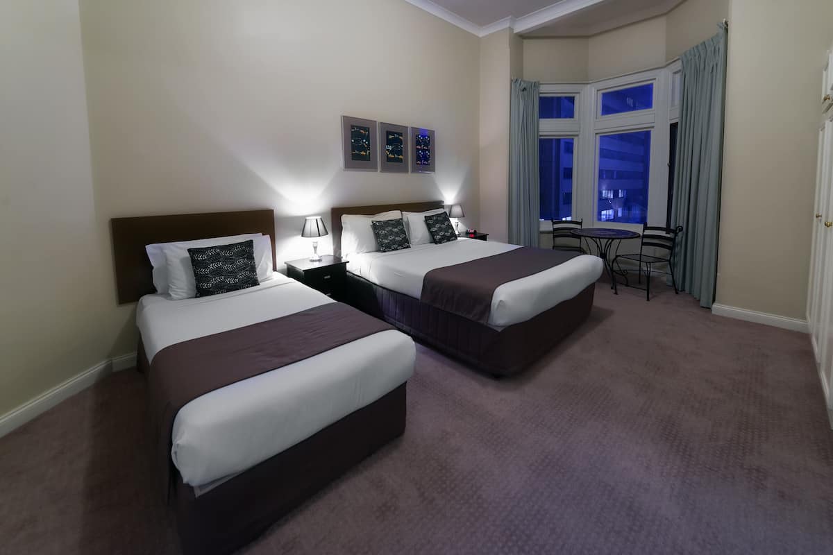 A hotel room with two beds, a desk, and a view of the city at night.