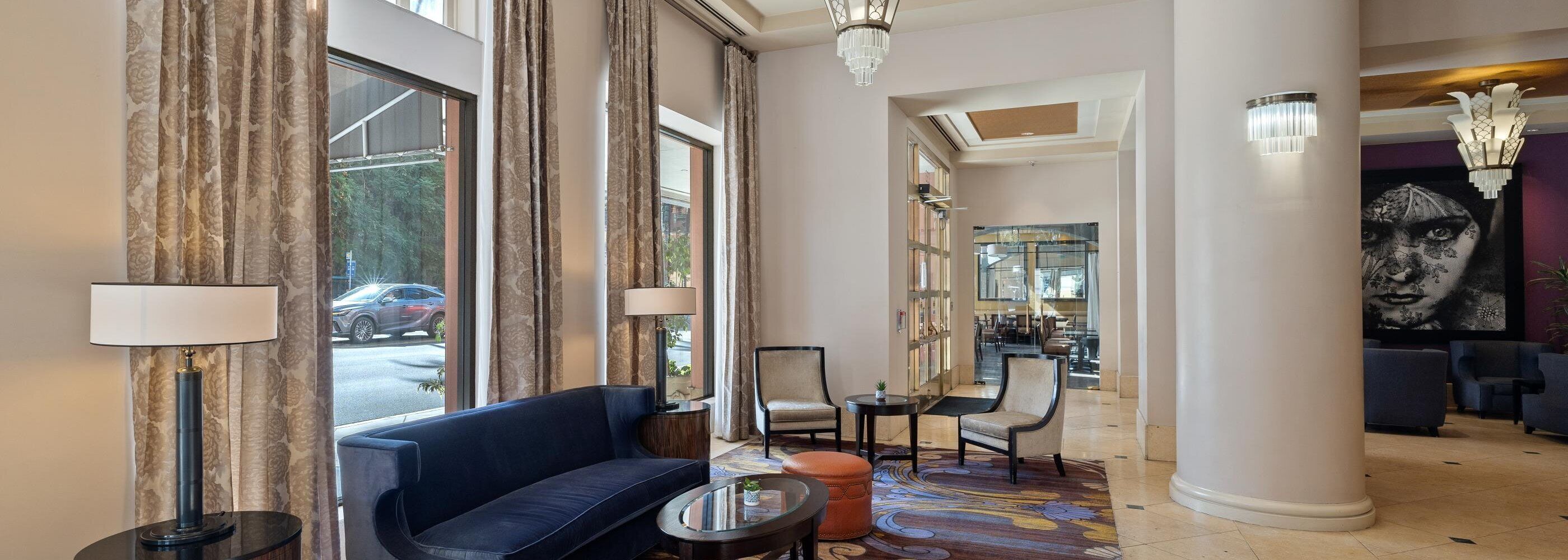 Un'ampia hall con un divano blu, un tavolino rotondo e un tappeto decorato.