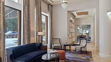 Un'ampia hall con un divano blu, un tavolino rotondo e un tappeto decorato.