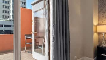 Ein Hotelzimmer mit einer Schiebetür zum Balkon, einem kleinen Tisch mit einem Stuhl, einer Lampe und einer Wand mit Musterpapier.